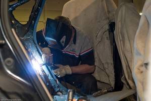 A welder working on a damaged car