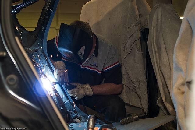 A welder working on a damaged car