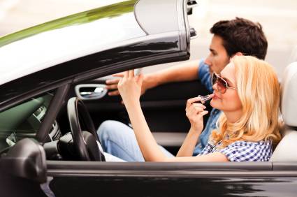 Young woman applying make up on her car Close up of a young woman applying make up on her car