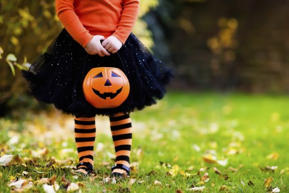 Little girl in witch costume playing in autumn park. Child having fun at Halloween trick or treat. Kids trick or treating. Toddler kid with jack-o-lantern. Children with candy bucket in fall forest.