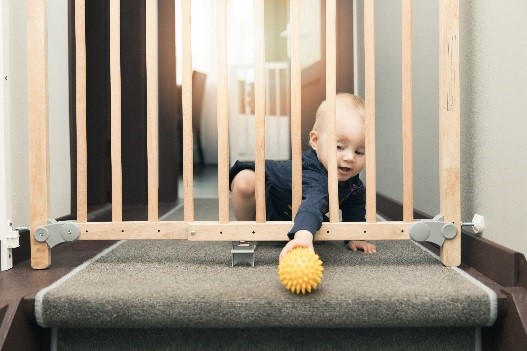 baby reaching through a gate for a toy