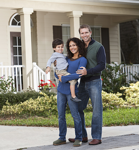 Family with little boy standing in front yard of home.