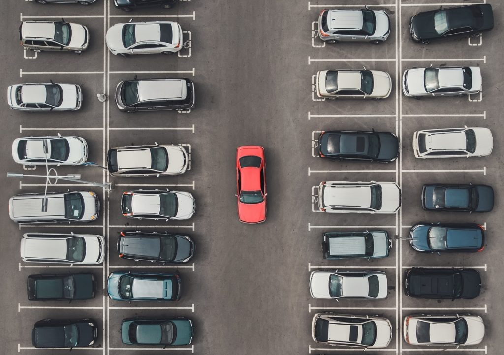 Top view of the crowded Parking lot with quadcopter or drone. Original bright automobile among the grey of mediocre cars. Parking space search, No parking space Auto Insurance