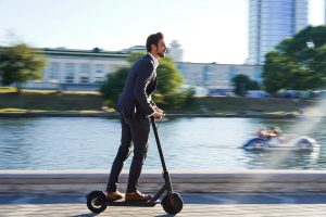 Business man riding electric scooter to work